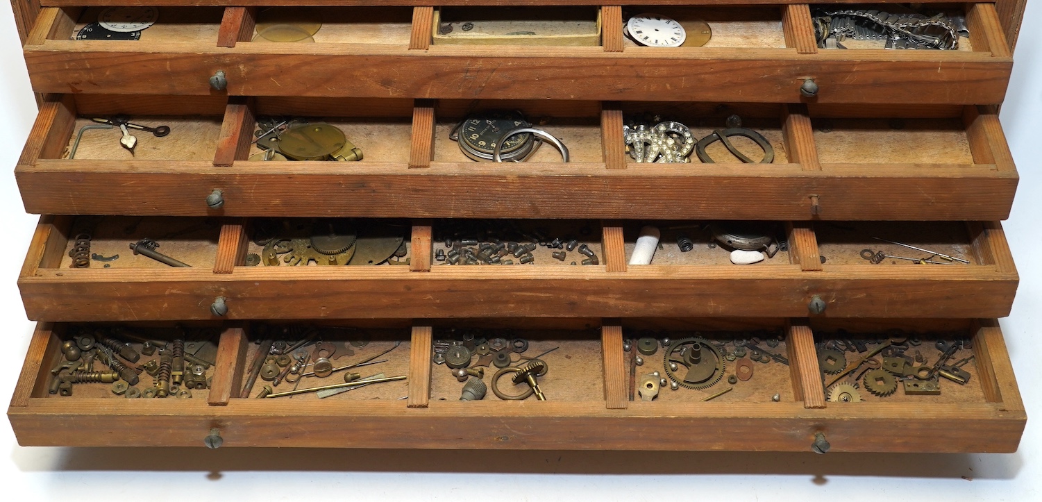 A wooden twelve drawer cabinet containing a collection of watch parts. Condition - cabinet fair to good, watch parts as found